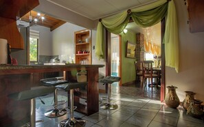 A kitchen with a bar area, bar stools, and a dining area with chairs. - Gato&Culla House (La Fortuna)