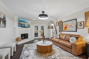 Ein Wohnzimmer mit Kamin, rundem Couchtisch, einer Couch und Kunstwerken an den Wänden.