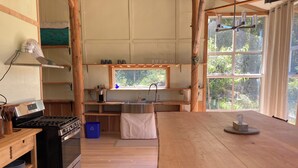 A kitchen with a wooden table, a stove, and a window with a view of greenery.
