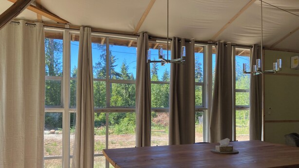 A room with large windows, a wooden table, and a chair.