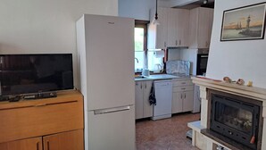 Eine kleine Küche mit Kühlschrank, Geschirrspüler und Kamin.