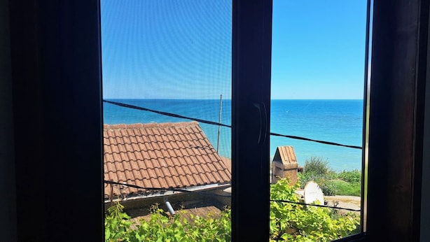 Blick durch ein Fenster auf einen klaren Himmel und ein entferntes Gewässer.