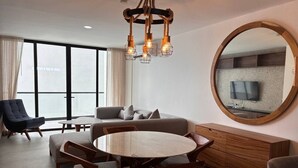 Un salon moderne avec une table ronde en bois, un canapé, un téléviseur et un grand miroir.