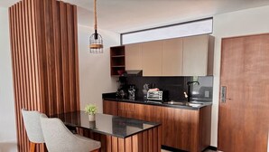 Une cuisine moderne avec des meubles en bois, un plan de travail noir et un petit îlot central agrémenté de deux chaises.