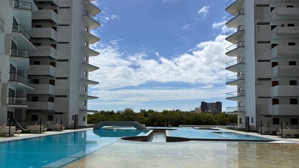 Un hôtel moderne doté d’une piscine centrale, de nombreux balcons et offrant une vue dégagée sur les environs.
