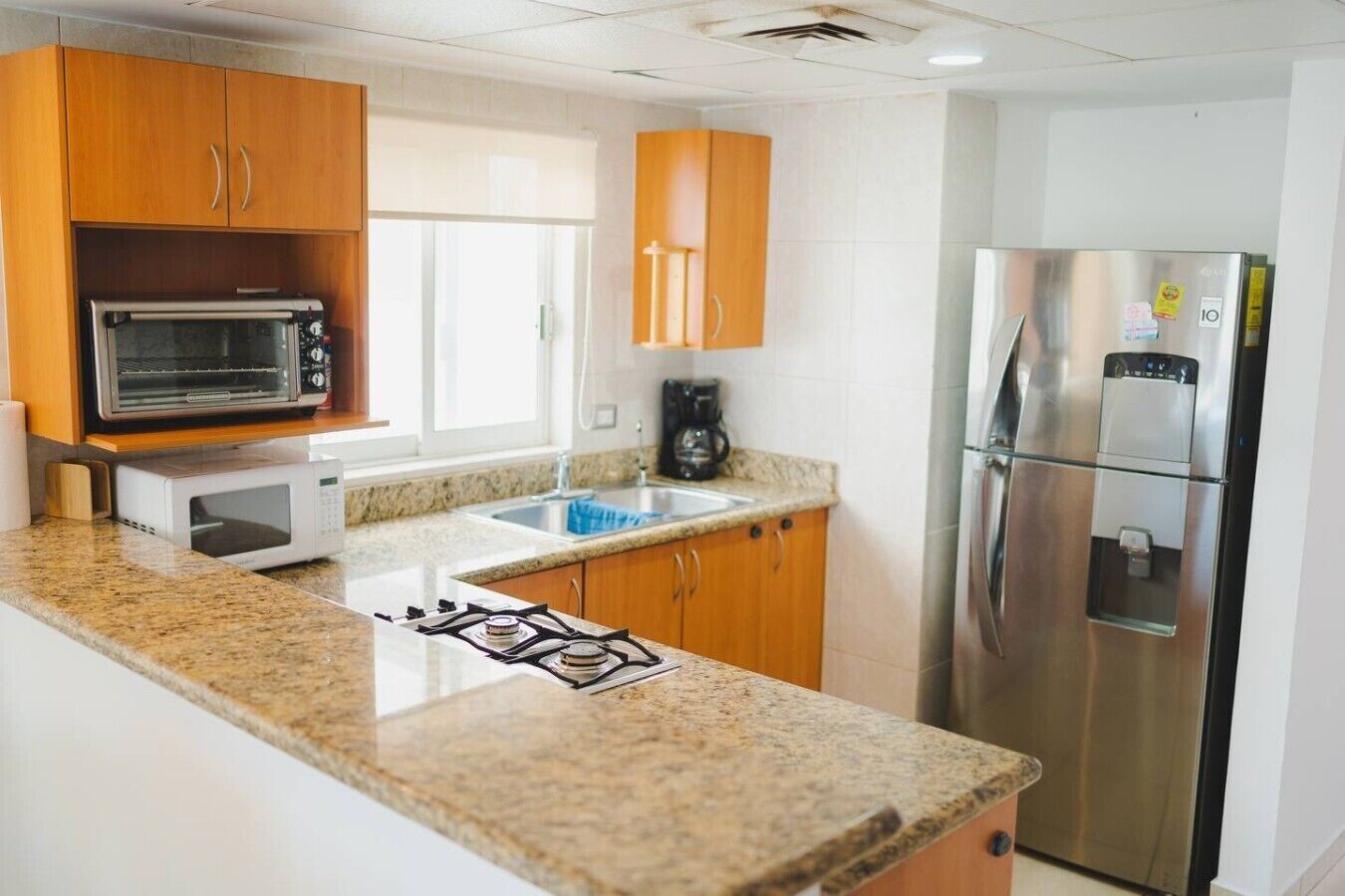 A kitchen with a microwave, stove, sink, and refrigerator.