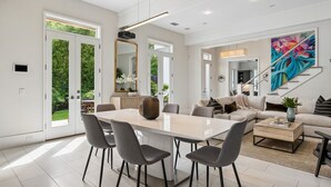 Un espacio habitable espacioso con una gran mesa de comedor, muebles modernos y un cuadro abstracto vibrante.