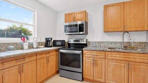 A kitchen with wooden cabinets, a stainless steel microwave, a stove, and a coffee maker. - Private 1BR Near Miami Airport with Free Parking (Hialeah)
