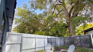 A backyard with a fenced area, two Adirondack chairs, and a small table. - Private 1BR Near Miami Airport with Free Parking (Hialeah)