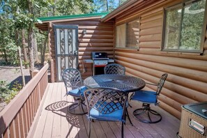 Eine Holzhütte mit einer Terrasse, einem Grill und Sitzgelegenheiten im Freien.