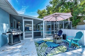 Ein Garten mit Grill, Sitzgelegenheiten im Freien, einem Pool und einer überdachten Terrasse.
