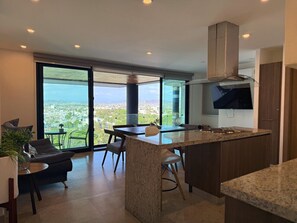 Una cocina moderna con una isla grande, comedor y vistas amplias a través de grandes ventanales.