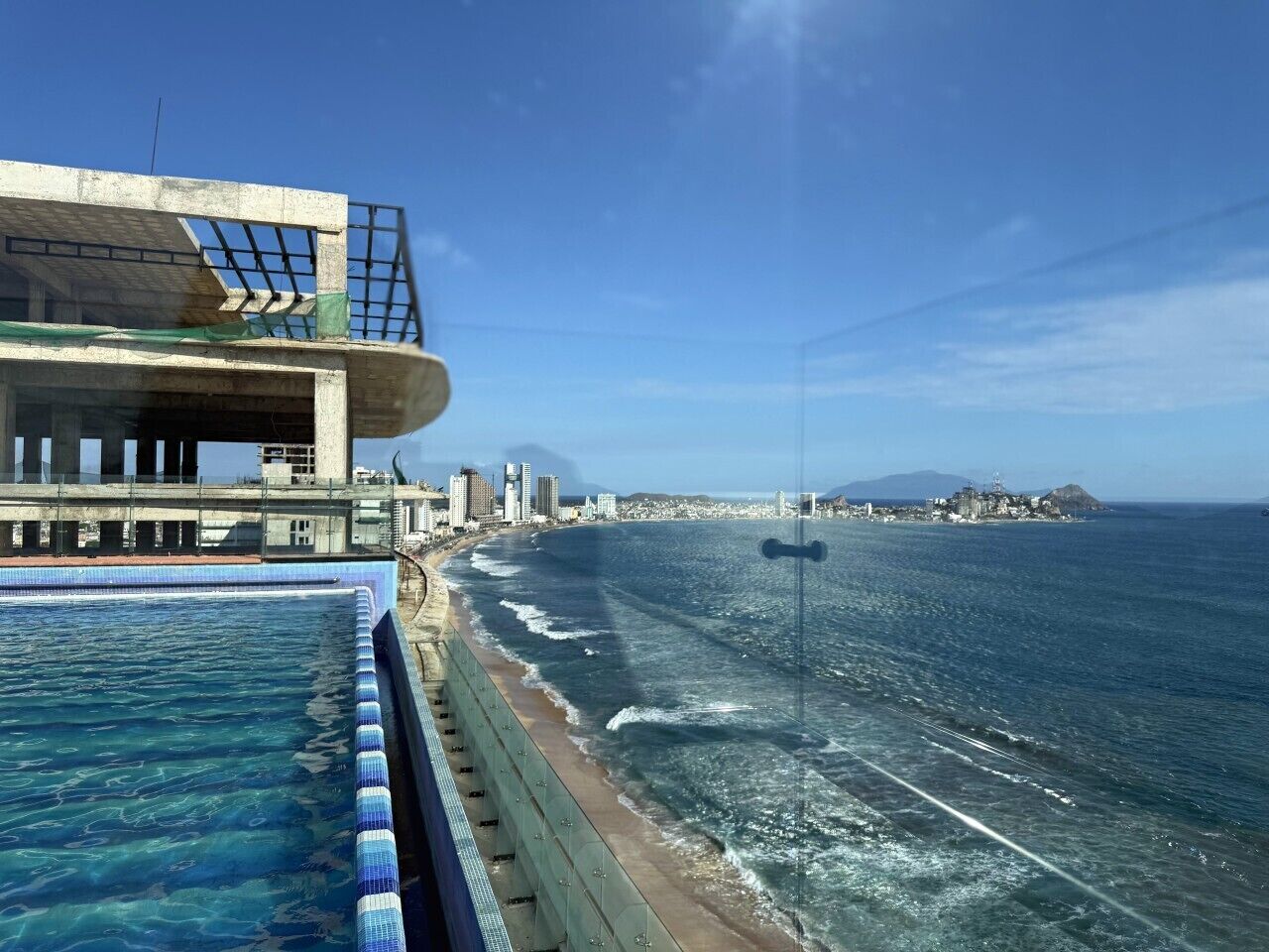 A coastal hotel with a pool, beachfront view, and a modern building structure.