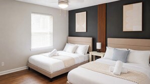 A hotel room with two beds, a nightstand, a lamp, and artwork on the walls. - The Monroe by Stylish Stays (Dallas)