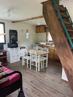 A kitchen with wooden cabinets, a dining table with chairs, a microwave, a stove, and a staircase. - Private Kenai River fishing, no combat fishing here!!!!! Comfy cabins too! (Soldotna)