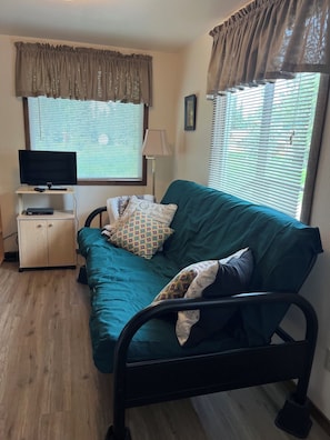 A room with a bed, a TV, a cabinet, and a window with curtains. - Private Kenai River fishing, no combat fishing here!!!!! Comfy cabins too! (Soldotna)