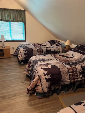 A room with two beds, a window with blinds, a lamp on a side table, and a wooden floor. - Private Kenai River fishing, no combat fishing here!!!!! Comfy cabins too! (Soldotna)