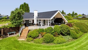 Ein modernes Haus mit einer überdachten Terrasse, einer Treppe und einem gepflegten Garten.
