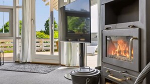 Ein modernes Interieur mit Kamin, Fernseher und Blick ins Freie.