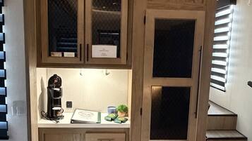 Una cucina compatta con mobili integrati, una macchina per caffè e un piccolo piano di lavoro.