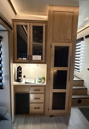 A compact kitchen with built-in cabinets, a coffee machine, and a small countertop.