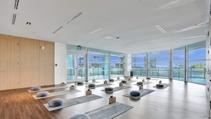 Ein großzügiger Yogaraum mit großen Fenstern, Holzböden und mehreren zur Nutzung bereitgelegten Yogamatten.
