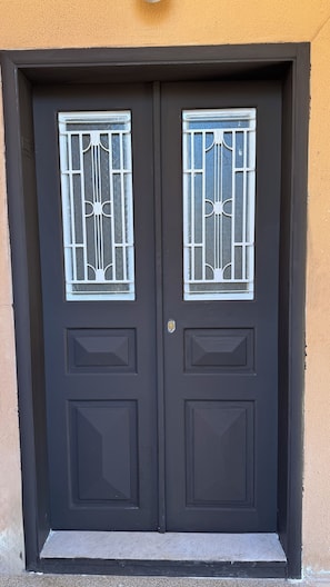 A dark-colored double door with decorative glass panels and a lock.
