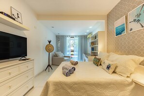 Ein Hotelzimmer mit Bett, Fernseher, weißem Schminktisch und Blick auf den Balkon.
