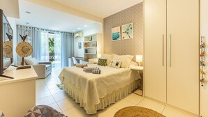 Ein Schlafzimmer mit Bett, Nachttischen, Schreibtisch, Stuhl, Kleiderschrank und einem fensterbepflanzten Fenster.