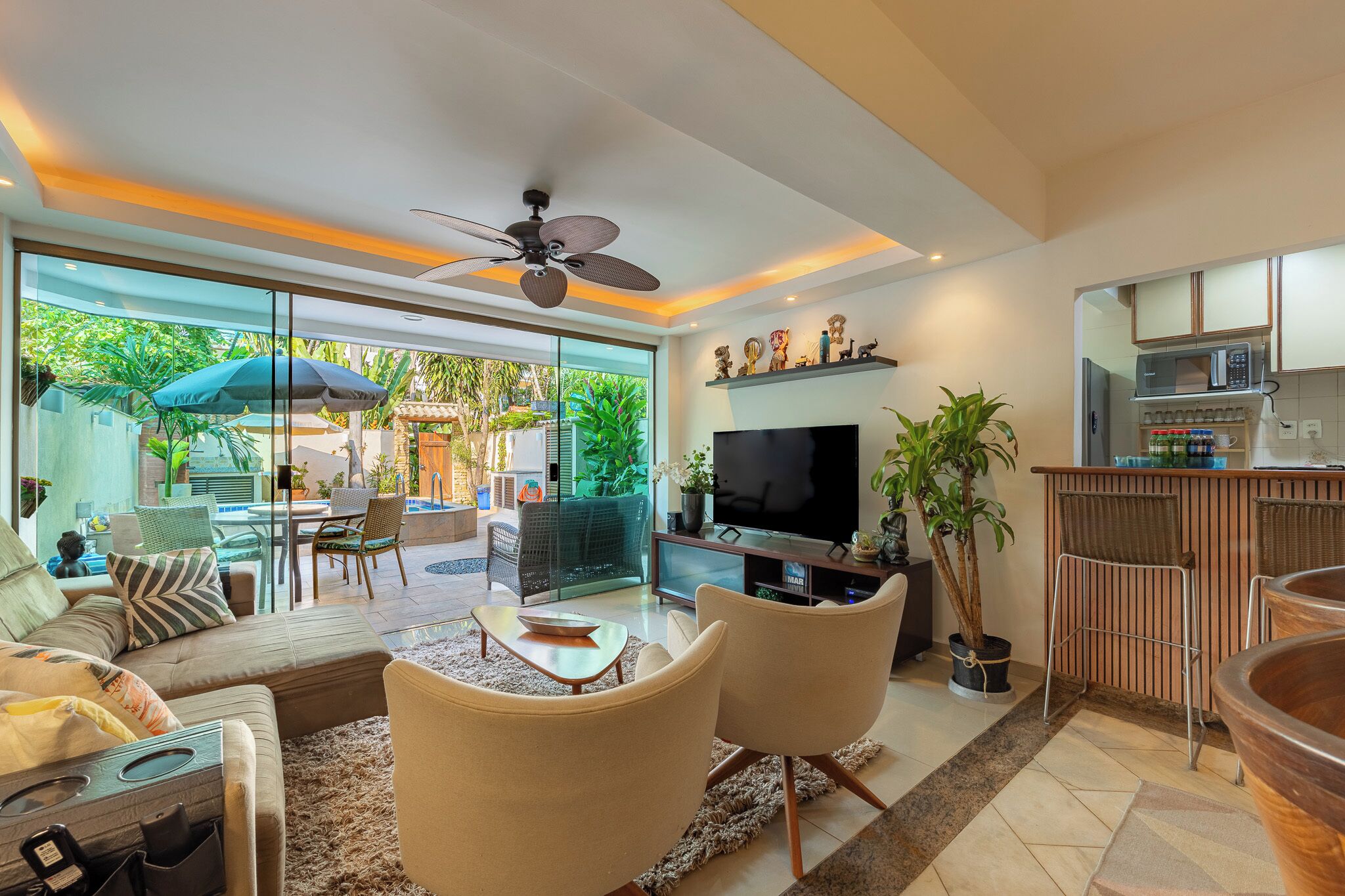 A modern living room with a TV, sofa, chairs, and a dining area with a table and chairs.