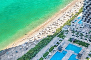Luftaufnahme eines Resorts mit Strand, Poolbereich und einem Gebäude mit Pool.