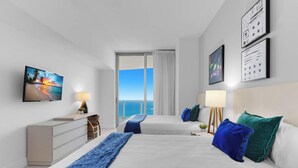 Una camera d'albergo con un letto, due comodini, una TV e vista sull'oceano.