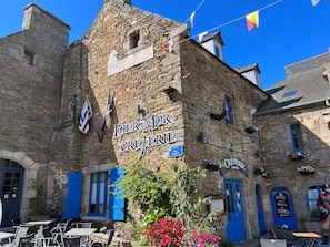 Un edificio histórico de piedra con un letrero que dice 'Laer-Mor Creperie'.