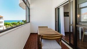 A balcony with a table and chairs, a sliding glass door, and a view of the ocean. - Blue Stay - 1º D by HelloVacations (Albufeira)