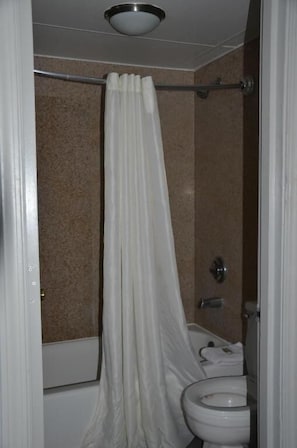 Un baño con cortina de ducha, inodoro y bañera.