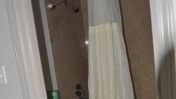 Une salle de bain équipée de toilettes, d’un rideau de douche et d’une poubelle visible.