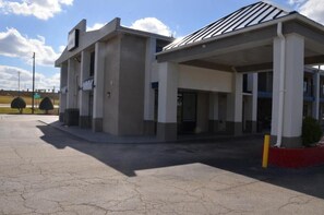 A gas station with a single-story building, a covered parking area, and a clear sky. - My Home and Suites Covington (Covington)
