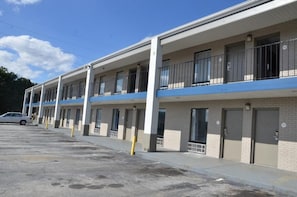 Un motel con varias habitaciones, un estacionamiento y cielo despejado.