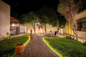 A courtyard with a paved walkway, potted plants, and a butterfly mural on the wall.