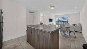 Una cocina moderna con encimera de granito, armarios de madera y una zona de comedor con mesa y sillas.