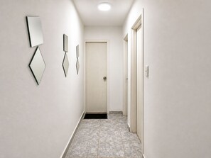 A hallway with a door at the end, tiled flooring, and wall-mounted mirrors. - Apartment for 4 people (Cartagena de Indias)