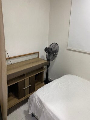 A bedroom with a bed, a wooden nightstand, a desk, and a standing fan. - Apartment for 4 people (Cartagena de Indias)