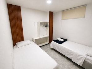A small, clean room with two beds, a mirror, a hanging towel, and a window. - Apartment for 4 people (Cartagena de Indias)