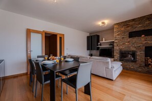 Ein moderner Wohnbereich mit Essbereich, einer Couch, einem Kamin und einer Küchenzeile.