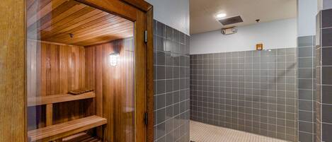A sauna with wooden benches and a tiled shower area.