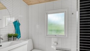 A bathroom with white tiled walls, a toilet, a window with a view, and a sink with a towel rack. - "Lucian" -  from the sea by Interhome (Hals)