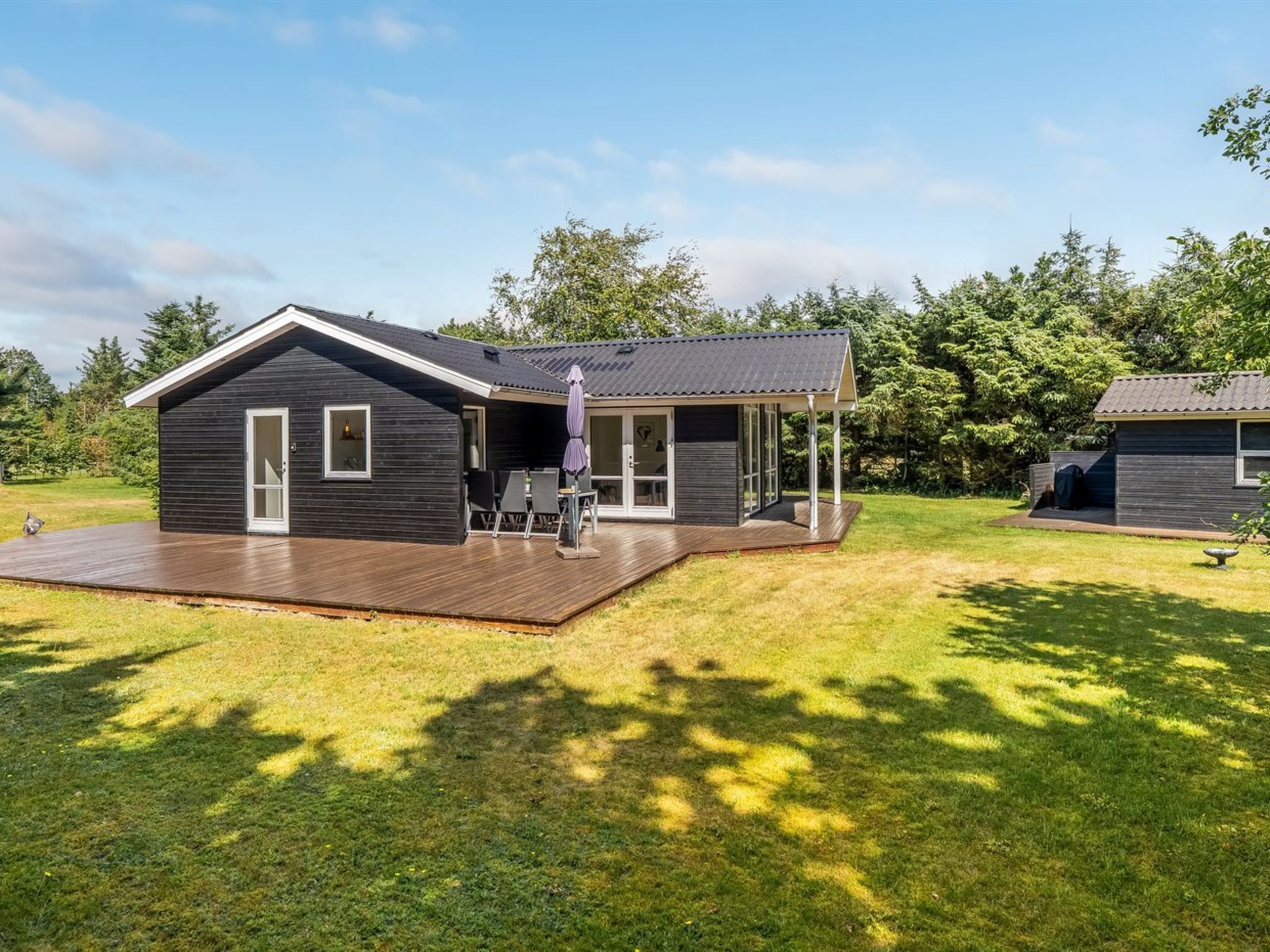 Une maison moderne dotée d’une terrasse, d’un patio couvert et d’un petit jardin.