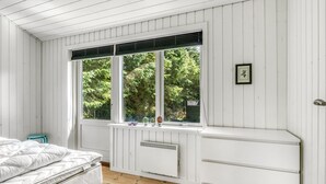 A bedroom with a bed, a window with blinds, a radiator, and a small stool. - "Lucian" -  from the sea by Interhome (Hals)