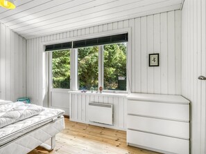 A bedroom with a bed, a window with blinds, a radiator, and a small stool. - "Lucian" -  from the sea by Interhome (Hals)