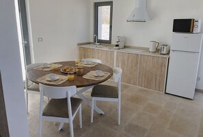 Ein Essbereich mit einem runden Tisch, weißen Stühlen und Frühstücksangeboten.